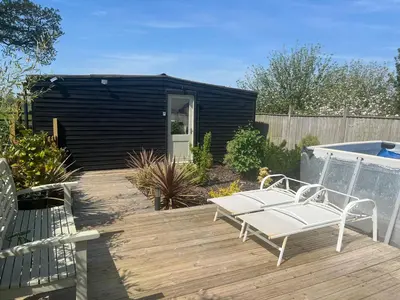 a patio with two chairs and a bench on a deck at Lavender Lodge - Pool and Hot Tub with sunset views over open fields in Wymondham