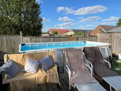 a patio table and chairs next to a swimming pool at Lavender Lodge - Pool and Hot Tub with sunset views over open fields in Wymondham