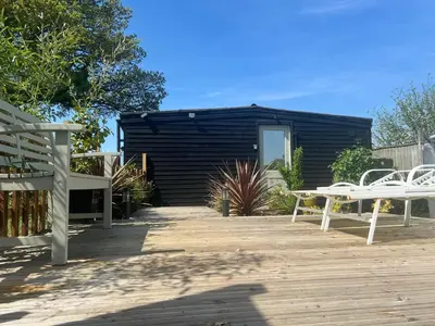 a patio with two white tables and a black building at Lavender Lodge - Pool and Hot Tub with sunset views over open fields in Wymondham