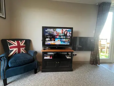 a flat screen tv sitting on a table next to a chair at Lavender Lodge - Pool and Hot Tub with sunset views over open fields in Wymondham