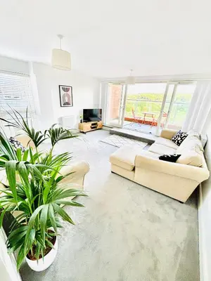 a living room with a couch and two potted plants at Riverside Haven in Woodbridge in Woodbridge