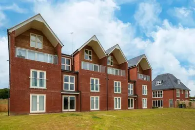 a large brick building on a grass field at Riverside Haven in Woodbridge in Woodbridge