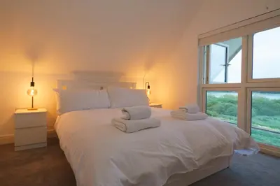 a bedroom with a large white bed with towels on it at Riverside Haven in Woodbridge in Woodbridge