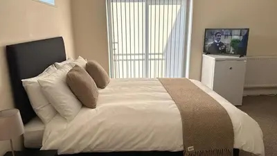 a bedroom with a white bed with pillows and a television at New Luxury flats in Ipswich