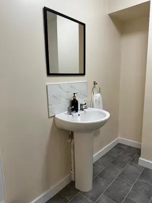a bathroom with a white sink and a mirror at New Luxury flats in Ipswich