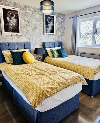 two beds in a bedroom with blue and yellow sheets at Kinlett close in Mile End