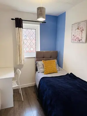 a bedroom with blue walls and a bed with a window at Kinlett close in Mile End