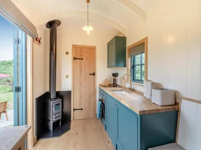 a kitchen with blue cabinets and a wood stove at Shepherd's Retreat in Ongar