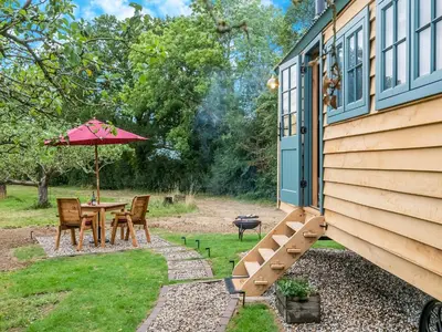 a patio with a table and an umbrella at Shepherd's Retreat in Ongar