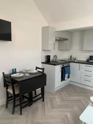 a kitchen with a table and chairs and a kitchen with white cabinets at Cosy Studio Apartment in Leigh-on-Sea, Close to Bell Wharf Beach & Adventure Island in Leigh-on-Sea