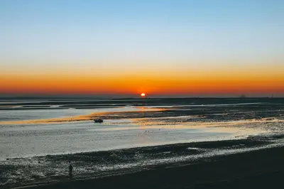 a sunset over a beach with the ocean at Cosy Studio Apartment in Leigh-on-Sea, Close to Bell Wharf Beach & Adventure Island in Leigh-on-Sea