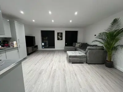 a living room with a couch and a palm tree at 1 Bedroom Apartment By Brookland Stays Serviced Accommodation Short Lets Essex With Free WIFI in Brentwood
