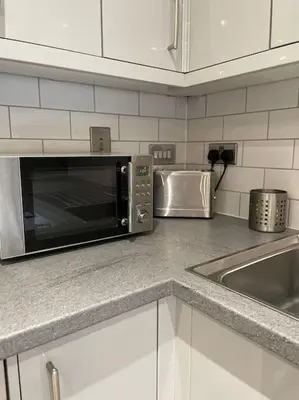 a kitchen counter with a microwave and a sink at 1 Bedroom Apartment By Brookland Stays Serviced Accommodation Short Lets Essex With Free WIFI in Brentwood