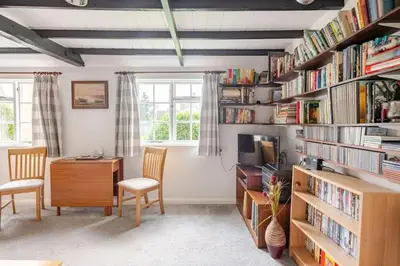 a room with a desk and chairs and bookshelves at Cozy One-Bedroom Cottage in Great Tey in Great Tey