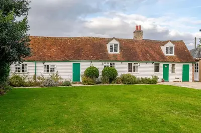 a white house with green shutters and a yard at Cozy One-Bedroom Cottage in Great Tey in Great Tey