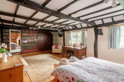 a bedroom with a large bed and a desk at Cozy One-Bedroom Cottage in Great Tey in Great Tey