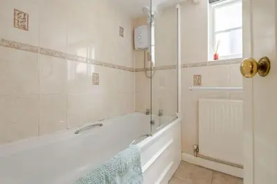 a bathroom with a bath tub and a sink at Cozy One-Bedroom Cottage in Great Tey in Great Tey