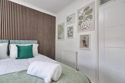 a bedroom with a bed with a green pillow on it at Rayleigh Weir - Luxury 3 bedroom house with games room in Rayleigh