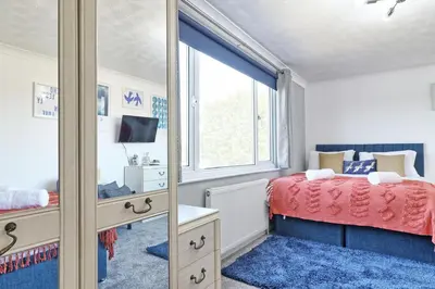 a bedroom with a bed and a mirror at Rayleigh Weir - Luxury 3 bedroom house with games room in Rayleigh