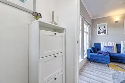 a white cabinet in a room with a blue couch at Rayleigh Weir - Luxury 3 bedroom house with games room in Rayleigh