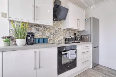 a kitchen with white cabinets and a stove at Rayleigh Weir - Luxury 3 bedroom house with games room in Rayleigh