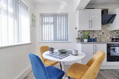 a kitchen and dining room with a white table and chairs at Rayleigh Weir - Luxury 3 bedroom house with games room in Rayleigh