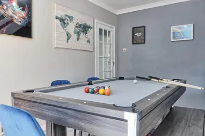 a pool table in a room with blue chairs at Rayleigh Weir - Luxury 3 bedroom house with games room in Rayleigh