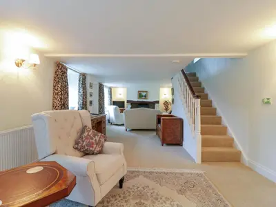 a living room with a staircase and a white chair at West View in Thetford