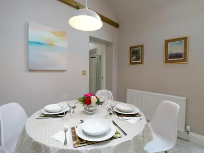 a dining room with a table with white chairs and a white tablecloth at West View in Thetford