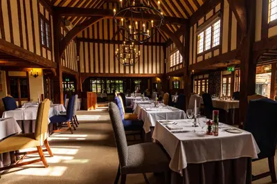 a dining room with tables and chairs and a chandelier at Swan Hotel & Spa in Lavenham