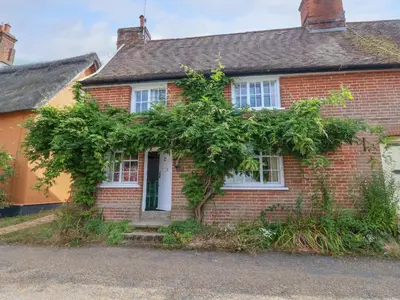 a red brick house with trees around it at Brook Cottage in Saxmundham