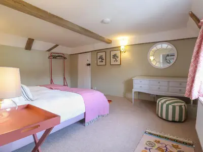 a bedroom with a bed and a table and a mirror at Brook Cottage in Saxmundham