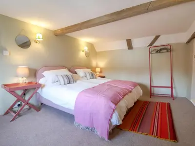 a bedroom with a large white bed and a table at Brook Cottage in Saxmundham