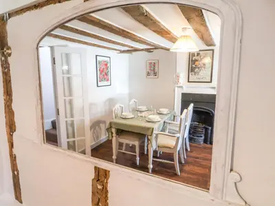 a dining room with a table and a mirror at Brook Cottage in Saxmundham