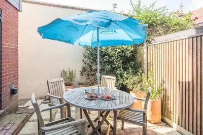 a table with a blue umbrella on a patio at Captain's Quarters, a ground floor apartment in Aldeburgh in Aldeburgh