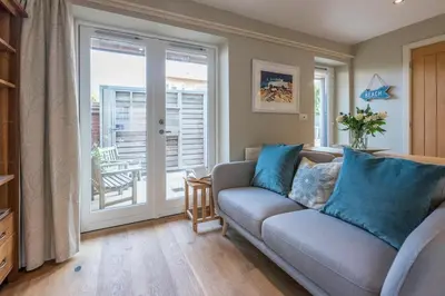 a living room with a couch and a sliding glass door at Captain's Quarters, a ground floor apartment in Aldeburgh in Aldeburgh