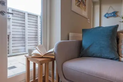 a living room with a couch and a book on a table at Captain's Quarters, a ground floor apartment in Aldeburgh in Aldeburgh