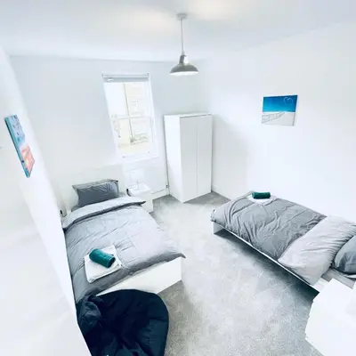 two beds in a room with white walls at 2 Bed Flat - Sleeps 5 - Parking - Wifi in Cambridge