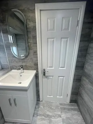 a bathroom with a sink and a white door at Cozy Studio Flat - Romford, London in Havering atte Bower