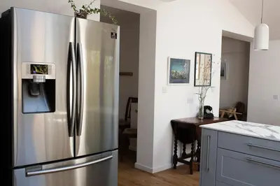 a stainless steel refrigerator in a kitchen with a table at 3 Bedroom House with Courtyard Garden and Parking in Chesterton