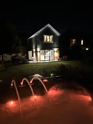 a house at night with a fountain in front of it at Beautiful family home with hot tub in Wivenhoe