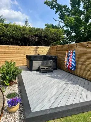 a wooden deck with a grill and an american flag at Beautiful family home with hot tub in Wivenhoe