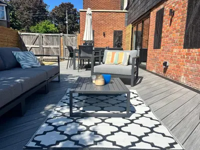 a patio with a couch and a table on a deck at Beautiful family home with hot tub in Wivenhoe