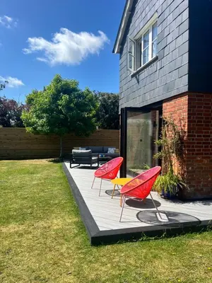 two red chairs and a table on a patio at Beautiful family home with hot tub in Wivenhoe