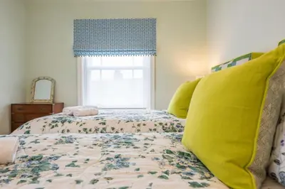 a bedroom with a bed with yellow pillows and a window at Rosebank, a stunning holiday home in Aldeburgh in Aldeburgh