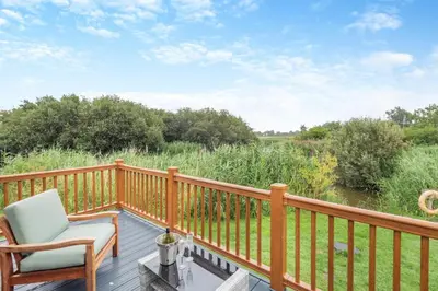 a deck with a chair and a view of a river at 2 Bed in Welney oc-s29764 in Welney