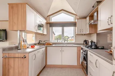 a kitchen with white cabinets and a large window at 2 Bed in Welney oc-s29764 in Welney