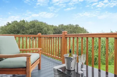 a deck with a chair and a table with a bottle of wine at 2 Bed in Welney oc-s29764 in Welney