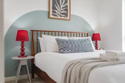 a bedroom with a bed and a table with two lamps at Stylish & Chic 3 bed House in Cambourne