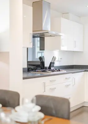 a kitchen with white cabinets and a wooden table at Stylish & Chic 3 bed House in Cambourne